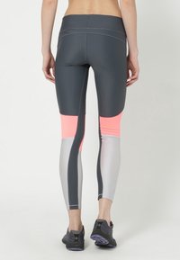 Leggings atletici grigi e argentei con accenti rosa; presentano un design aderente, materiale elasticizzato e pannelli di colore a contrasto.