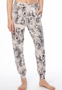 Lässige Jogginghosen aus weichem Stoff, mit beigem Hintergrund und detaillierten schwarzen Illustrationen, seitlichen Taschen und elastischen Bündchen an den Knöcheln.