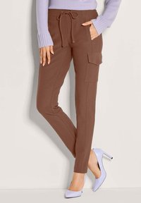 Bruine cargobroek met een verstelbare taille, zijzakken en taps toelopende benen, gecombineerd met lavendelkleurige hoge hakken. Gladde textuur, minimale details.