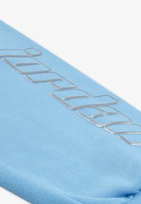 Textil de culoare albastru deschis, cu o textură fină, având litere argintii embosate. Designul este simplu, cu o formă rectangulară și margini curate.