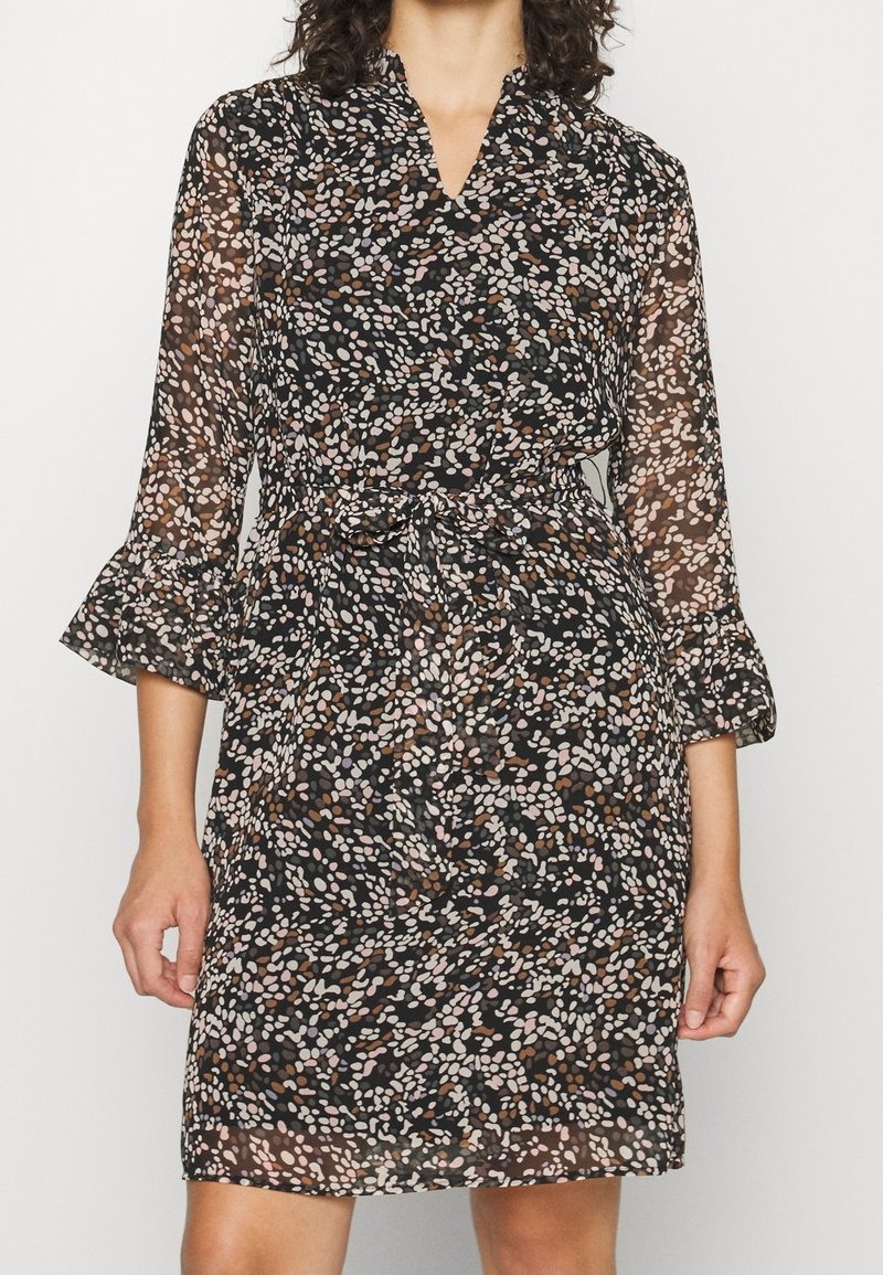 Czarna sukienka w kwiatowy wzór w beżowe, różowe i brązowe odcienie. Posiada długie rękawy, dekolt w serek oraz wiązanie w talii. Przezroczysta tkanina z falbanianymi mankietami.