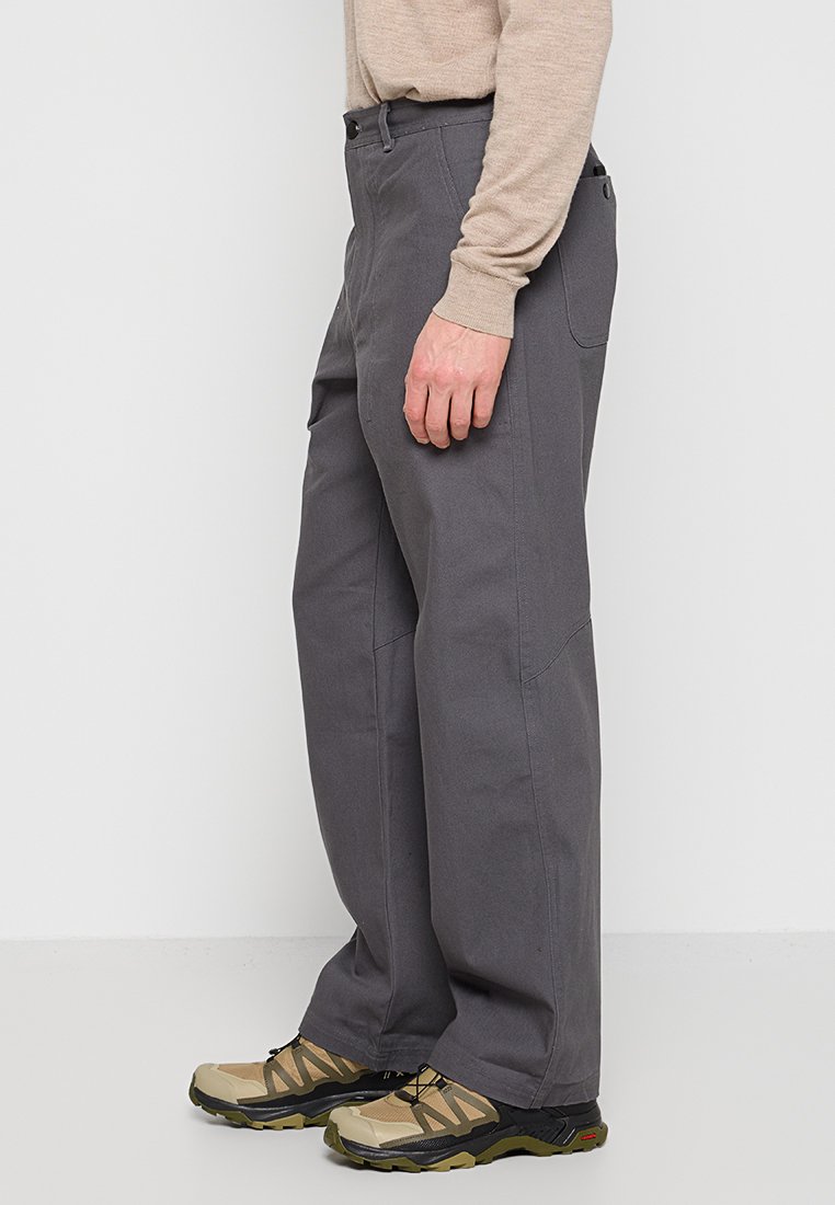 Pantalones grises de corte relajado, hechos de un tejido duradero, con un diseño de pierna recta, bolsillos laterales y detalles de costura mínimos.