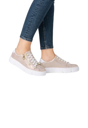 Baskets beige clair avec une finition texturée, semelle blanche et détail de fermeture éclair doré. Design à lacets avec lacets blancs plats. Jeans de couleur bleu foncé.