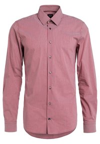 Chemise à manches longues à rayures verticales rouges et blanches, dotée d'un col classique et de boutons noirs, avec une texture en coton lisse.