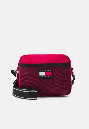Kleine rechteckige rote Umhängetasche mit schwarzer Netz-Vordertasche, schwarz-weiß verstellbarem Schultergurt und Tommy Jeans Logo-Patch.