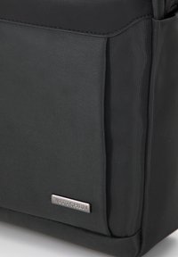 Borsa nera in nylon con superficie testurizzata, dotata di una parte superiore liscia, tasca laterale e una placca del logo del marchio in metallo.