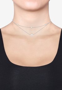 Layered silver necklaces featuring a crescent moon pendant and star accents on delicate chains, showcasing a polished metallic finish.