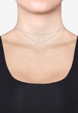 Layered silver necklaces featuring a crescent moon pendant and star accents on delicate chains, showcasing a polished metallic finish.