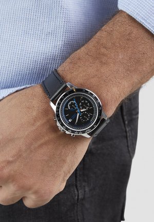 Chronograafhorloge met een zwarte wijzerplaat, zilverkleurige kast en blauwe accenten. Voorzien van een zwarte leren band en een tachymetrische schaal op de lunette.