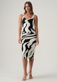 Strick-Midi-Kleid mit einem schwarz-weißen, gewellten Zebra-Muster, ausgestattet mit einem Rundhalsausschnitt und Schulterträgern, aus weichem Stoff gefertigt.