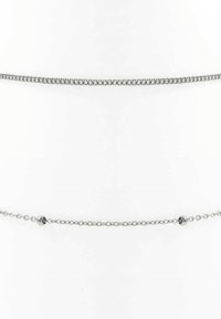 Zilveren kettingjuwelen met een dikke, in elkaar grijpen curb ketting aan de bovenkant en een delicaat bolletjesketting met kleine bolvormige accenten eronder.