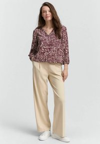 Long-sleeve maroon blouse with a textured pattern, paired with beige high-waisted trousers and white sneakers.