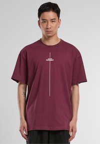 Burgundy cotton t-shirt with short sleeves, featuring a horizontal white text graphic that reads "I THINK DIFFERENT." Centered design.