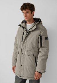 Hellgrauer isolierter Parka mit Kapuze, vorderen Knopf- und Reißverschluss, mehreren Taschen und schwarzen Akzenten an Reißverschlüssen und Ärmeln.