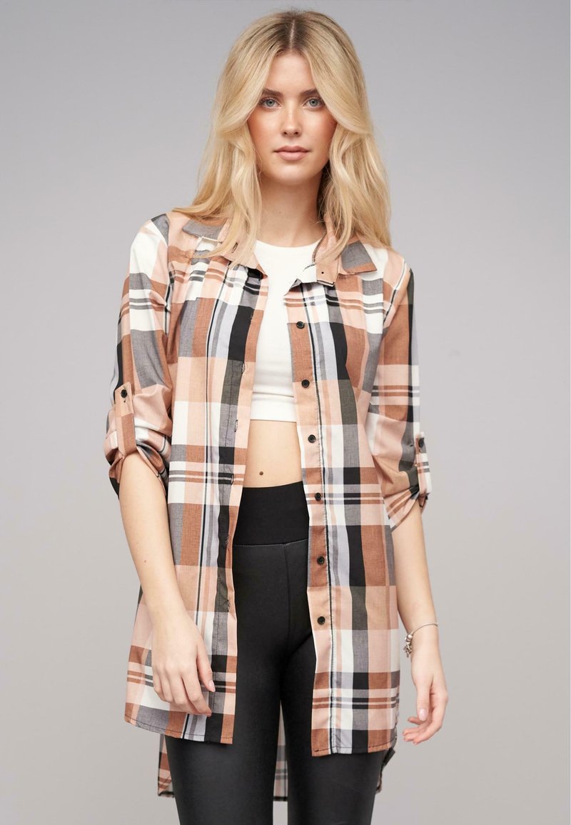 Rutet skjorte i fersken, sort og creme med opbrettede ærmer, parret med en hvid crop top og sorte leggings. Glat stoftekstur.