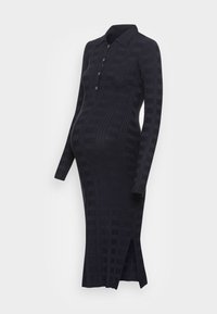 Robe de maternité bleu marine côtelée avec un col à revers, une patte de boutonnage, des manches longues et des fentes latérales pour faciliter les mouvements. Texture uniforme sur toute la surface.