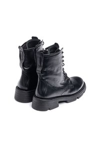 Botas de tobillo de cuero negro con un acabado texturizado, cordones en la parte frontal, cremallera lateral y una suela gruesa con relieve. Dos lengüetas en el collar.