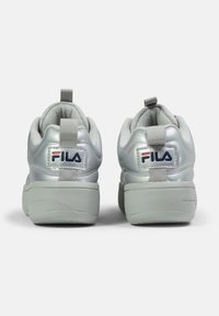 Sneakers metallici argento con superficie texturizzata, collo imbottito, suola bianca e dettagli del logo sul tallone e sul lato.