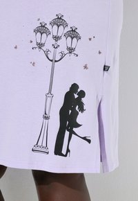 Jasnofioletowa koszulka z czarnymi nadrukowanymi sylwetkami pary przy ozdobnej latarni ulicznej, z drobnymi brokatowymi akcentami rozmieszczonymi dookoła.