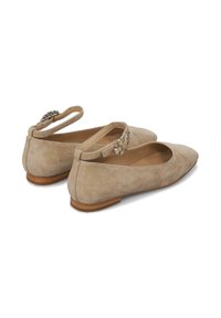 Bailarinas de ante beige con punta afilada, tiras en el tobillo y adornos decorativos en la parte trasera. Cuenta con un bajo tacón de madera.