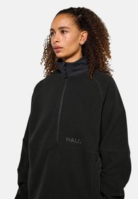 Zwarte fleece pullover met een hoge kraag, halve rits en subtiele "HALO"-logo. Beschikt over contrasterende stof en een ontspannen pasvorm.