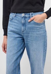 Ljusblå denimjeans med rak passform, som har fem fickor, synlig söm och en silvrig knappstängning i midjan.