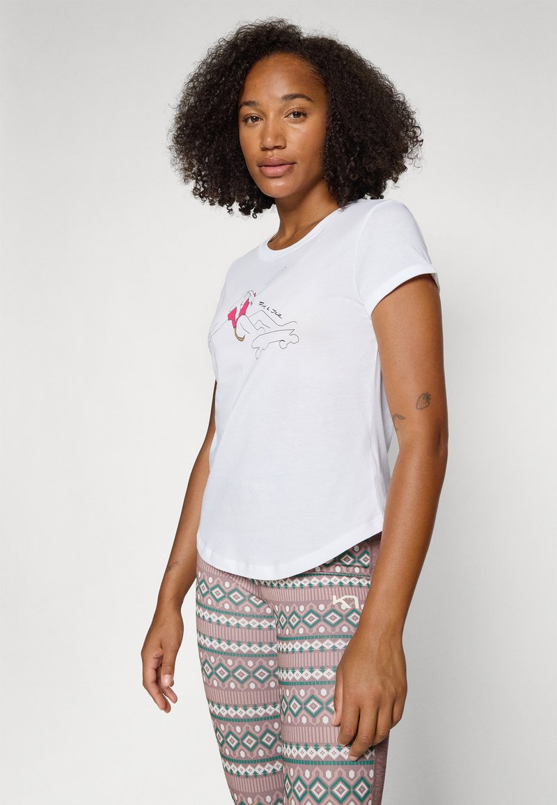Weißes Baumwoll-T-Shirt mit kurzen Ärmeln, das ein farbenfrohes Grafikdesign auf der Vorderseite zeigt. Kombiniert mit gemusterten Leggings in Pastellfarben.