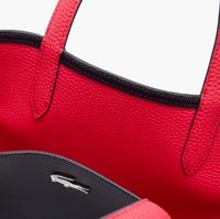Sac fourre-tout en cuir texturé rouge avec des finitions noires, doté de deux poignées et d'un intérieur en tissu noir. Logo Lacoste visible à l'intérieur.