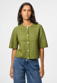 Cardigan en tricot vert à manches courtes avec texture côtelée, décolleté rond et cinq boutons blancs sur le devant. Associé à un jean en denim bleu.