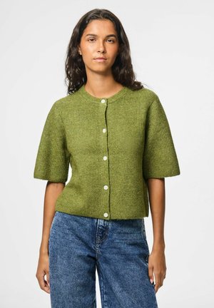 Groene gebreide korte mouwen cardigan met ribbelstructuur, ronde halslijn en vijf witte knopen aan de voorkant. Gecombineerd met blauwe denim.