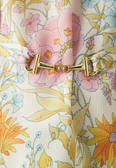 Stoff mit Floralmustern, der rosa, orange und blaue Blumen auf einem hellen Hintergrund zeigt, gesichert mit einem goldenen Hardware-Verschluss.