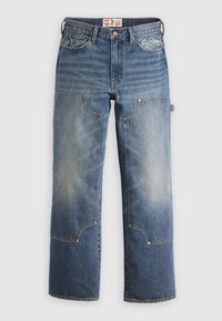 Jeans de mezclilla azul con un corte holgado, que presentan grandes bolsillos parcheados, herrajes de latón y patrones de costura distintivos. Logo bordado en la cintura.