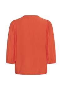 Blouse orange à manches longues avec poignets froncés et léger détail d'épaule bouffante, vue de dos sur fond blanc.