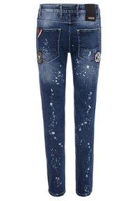 Jean en denim bleu foncé avec des détails usés, des motifs éclaboussés et des patchs brodés. Comprend cinq poches et un design à jambe droite.