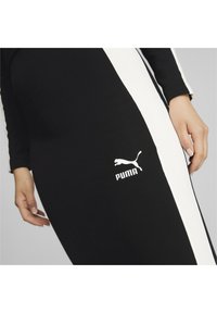Abito a maniche lunghe in bianco e nero realizzato in tessuto elasticizzato, con design a strisce laterali e logo Puma bianco sul davanti.