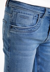 Lichtblauwe denim jeans met een klassiek vijf-pocket ontwerp. Voorzien van reliëfbranding op de achterzak en subtiele whiskeringdetail.