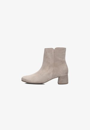 Botte de cheville en cuir suédé beige avec un bout rond et un talon bloc. Présente une texture lisse et des détails de couture minimaux, avec une fermeture éclair à l'arrière.