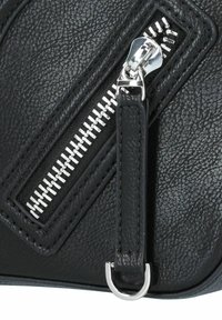 Bolso de cuero negro con acabado texturizado, detalle de cremallera diagonal, herrajes de plata y una correa de cuero con un acento de anillo metálico.