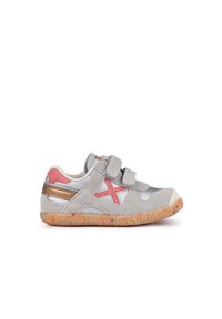 Zapato de ante gris con acentos rosas, correas de Velcro y una suela texturizada. Presenta un panel plateado y un diseño de cruz roja destacado.