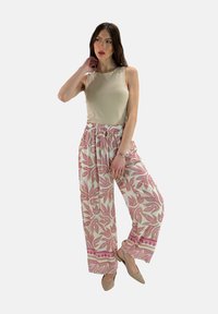 Beige mouwloze top met lichtroze bloempatronen wijde broek met een elastiche tailleband en trekkoorddetails.