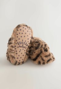 Chaussons en fausse fourrure au motif léopard marron et noir avec une texture douce. Dotés d'un dessous rembourré beige avec des points foncés et une marque imprimée.