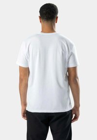 Hvid kortærmet t-shirt lavet af bomuld, med en almindelig rund hals og en afslappet pasform. Bagsiden viser en glat tekstur og minimalt design.