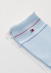 Lyseblå bomullssokker med ribbestrikkede mansjetter, prydet med flerfargede striper og en liten logo. Myk tekstur med en jevn finish.