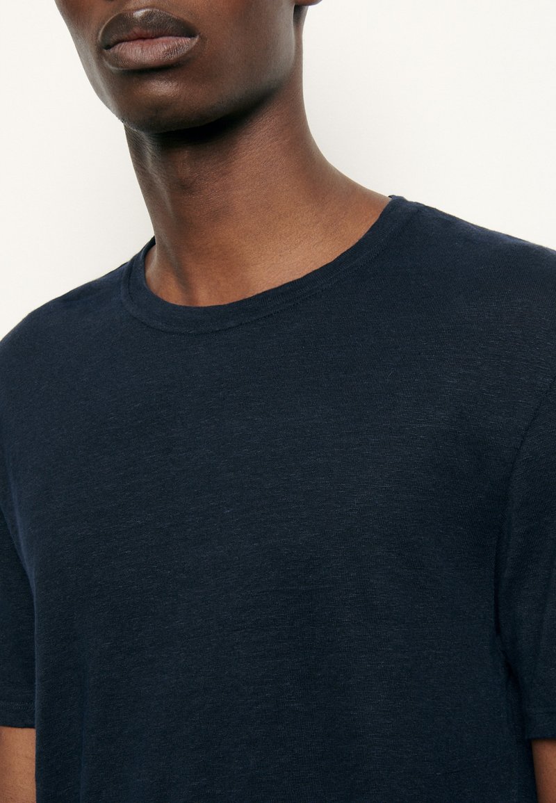 Camiseta de manga corta de color azul marino, hecha de una tela suave, con una textura lisa y un cuello redondo clásico. Diseño minimalista sin patrones.