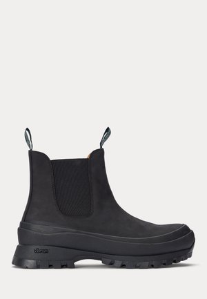 Bottes de Chelsea noires en caoutchouc, imperméables, avec des panneaux latéraux élastiques texturés et des languettes de tirage. Présentant une semelle à crampons épaisse pour une meilleure adhérence.