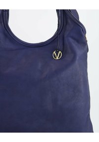 Paarse leren totebag met een gladde textuur, voorzien van een ovale handgreep en een gouden bedeltje met een merklogo eraan bevestigd.
