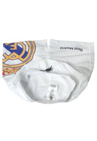 Biała czapka z logo Real Madryt w niebieskim i żółtym kolorze z jednej strony. Zawiera regulowany elastyczny pasek oraz wewnętrzną podszewkę z siatki.