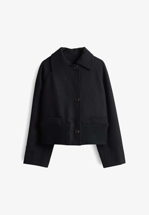 Schwarze, kurzes Jacket aus strukturiertem Stoff mit umgeschlagenem Kragen, Knopfverschluss sowie geripptem grünen Saum und Bündchen. Mit Fronttaschen.