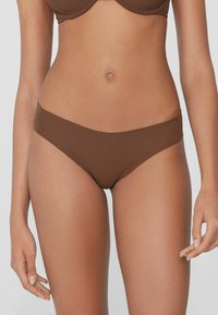 Brązowe, bezszwowe majtki bikini wykonane z miękkiego materiału. Charakteryzują się minimalistycznym wzornictwem, średnim pokryciem i gładką teksturą.