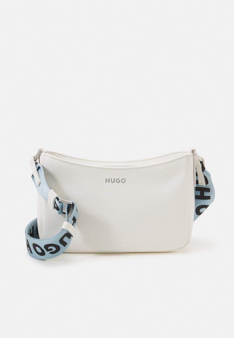 Bílá kožená taška přes rameno s nastavitelným světle modrým popruhem, zdobená černým textem "HUGO" a zapínáním na zip na vrchu.